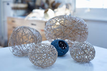 Load image into Gallery viewer, An assortment of completed random weave baskets placed on a white table, all of which are white except for a small dark blue one.
