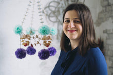 Load image into Gallery viewer, Karolina Merska standing in front of one of her Pajaki paper chandelier creations.
