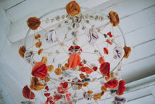 Load image into Gallery viewer, A completed pajaki paper chandelier with paper roses hanging from the ceiling. 
