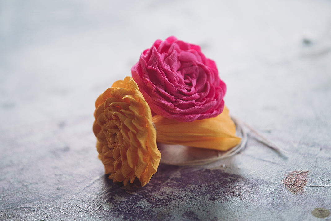 Two completed paper roses, in bright pink and orange.