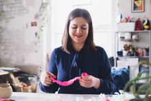 Load image into Gallery viewer, Karolina assembling a paper rose using pink tissue paper.
