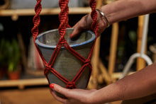 Load image into Gallery viewer, Testing out the size of the spiral knot macrame hanger with brick coloured rope to make sure the pot fits.
