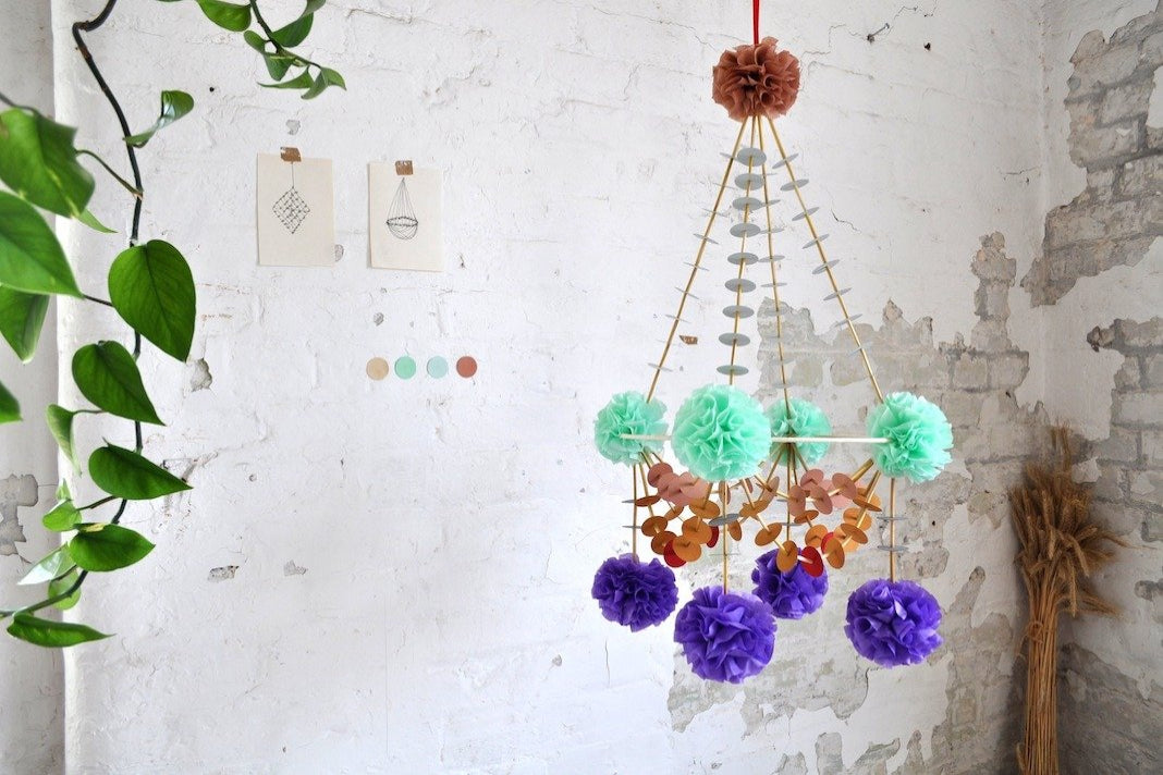 A pajaki chandelier with bright mint, purple and orange pompoms.