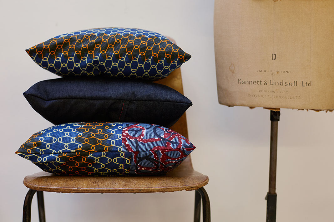 Three patterned cushions stacked on top of each other on a chair.