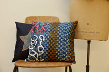 Load image into Gallery viewer, Two ornate square denim cushions posed on a chair. 
